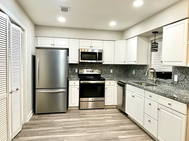 a kitchen with granite countertop a refrigerator stove and microwave