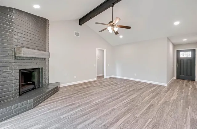 a view of an empty room with wooden floor fireplace and a window