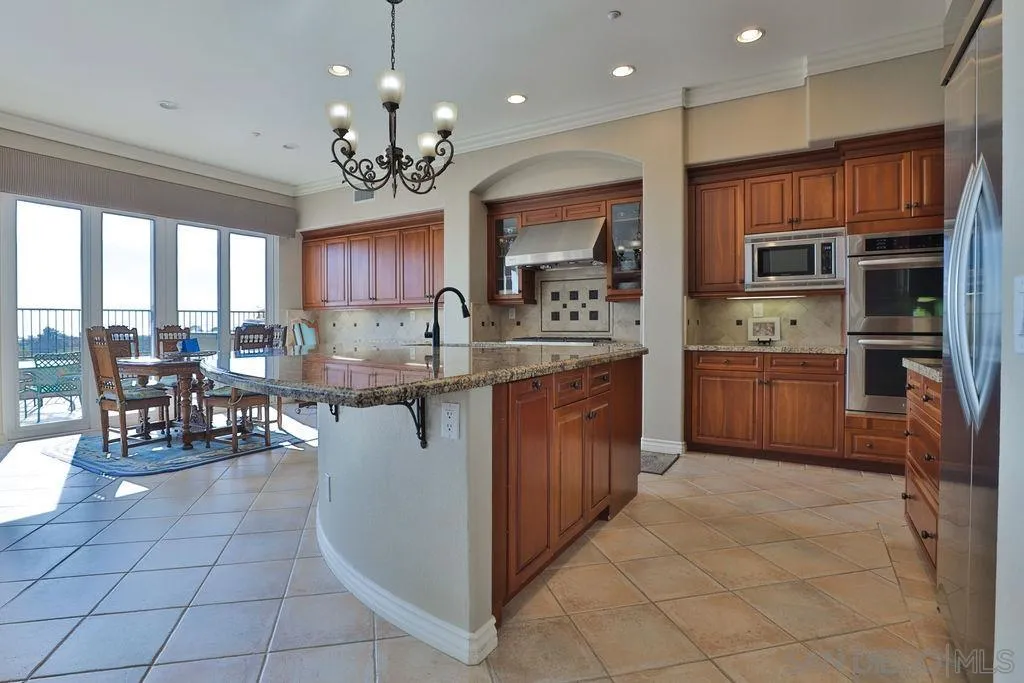 1375 Ravean Court Encinitas, CA 92024 - Photo 33 of 73 a kitchen with stainless steel appliances granite countertop a stove top oven a sink dishwasher a dining table and chairs cabinets with wooden floor