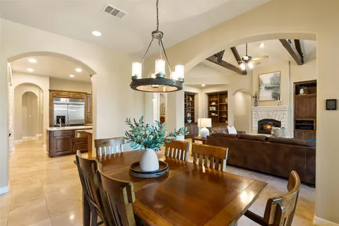 a dining room with wooden floor a chandelier a wooden table and chairs