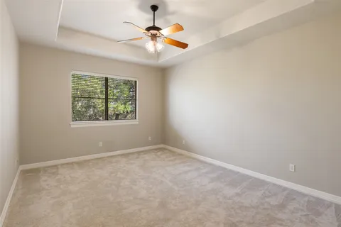 an empty room with windows and chandelier fan