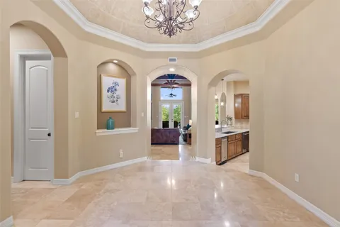 a view of a hallway with entryway windows chandelier and a kitchen view