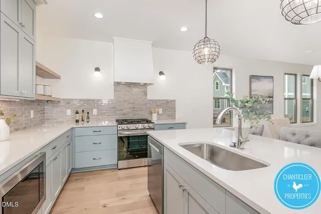 a large kitchen with a sink and dishwasher with white cabinets