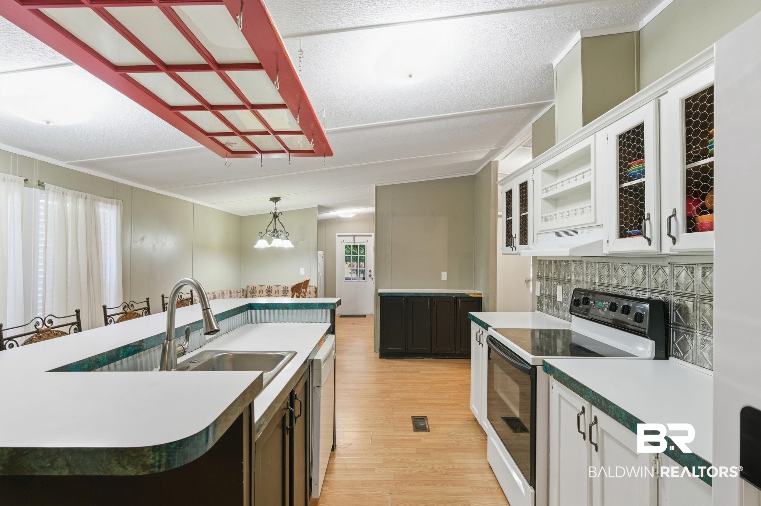 926 Tumbling Lane Atmore, AL 36502 - Photo 20 of 56 Kitchen featuring an integrated breakfast bar, stainless steel sink, white cabinetry with chicken wire inserts, a tile backsplash, and wood-finish flooring