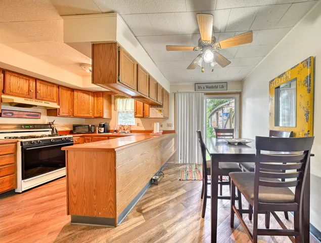 a kitchen with stainless steel appliances granite countertop a stove top oven a sink dishwasher and white cabinets with wooden floor