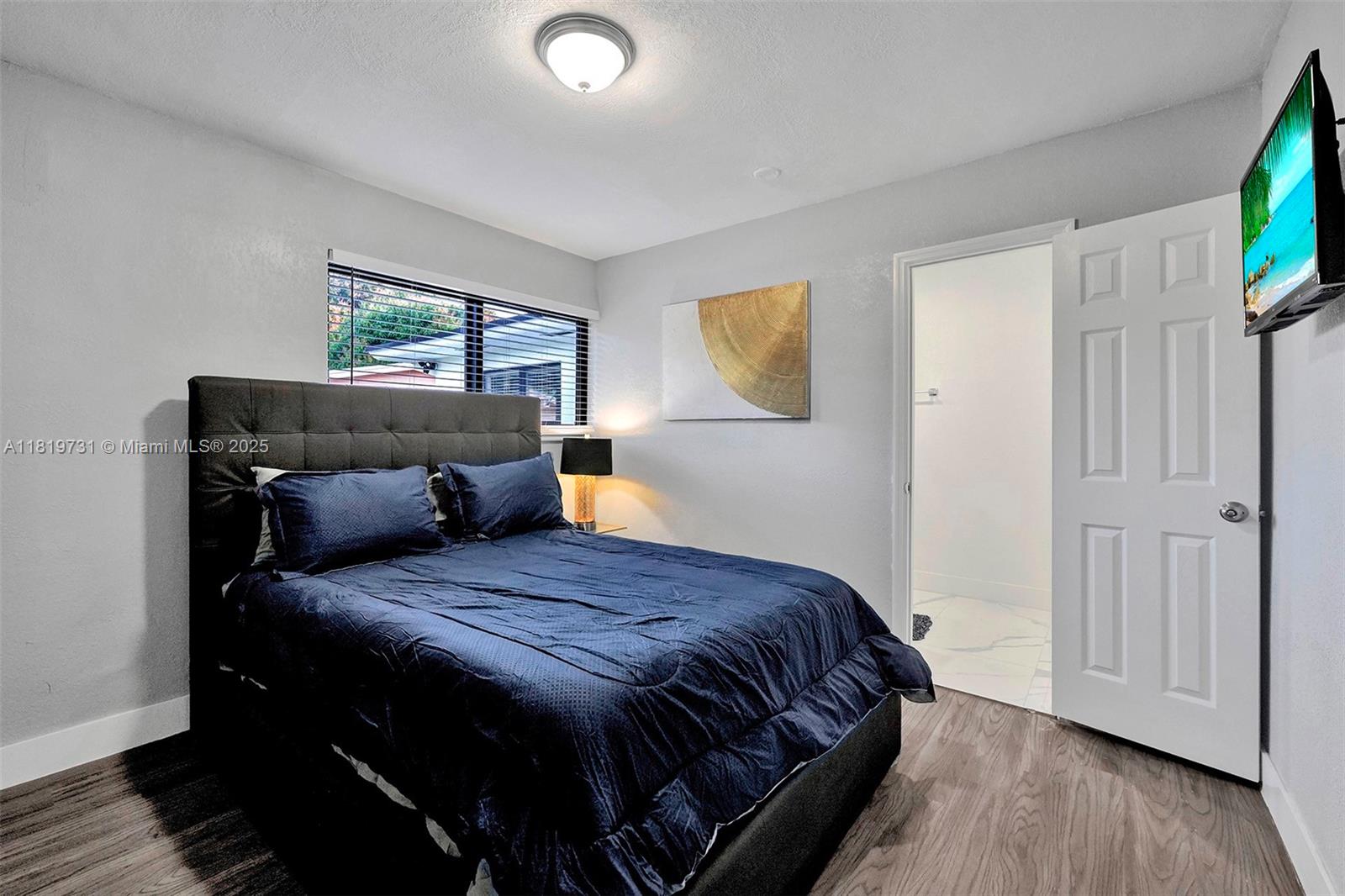 1324 Northeast 151st Street, Unit 1324 Miami, FL 33162 - Photo 7 of 23 a bedroom with a bed and wooden floor