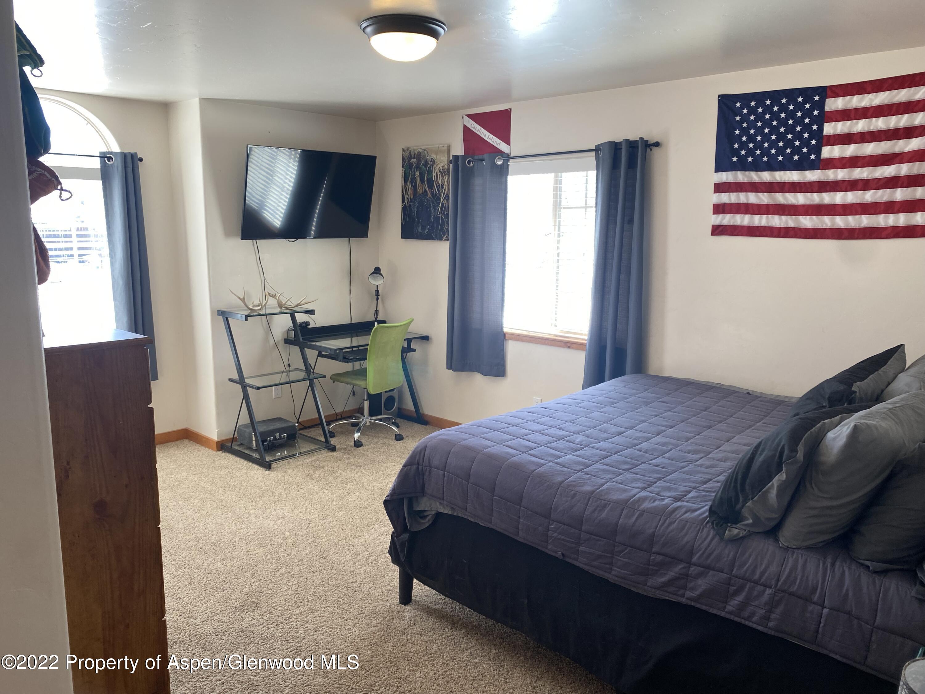 858 East 17th Street Rifle, CO 81650 - Photo 8 of 20 a bedroom with a bed a chair and potted plant on the dresser
