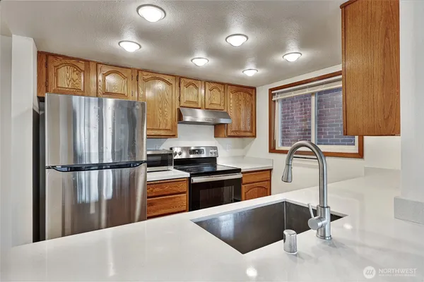 a kitchen with stainless steel appliances granite countertop a refrigerator sink stove microwave and cabinets
