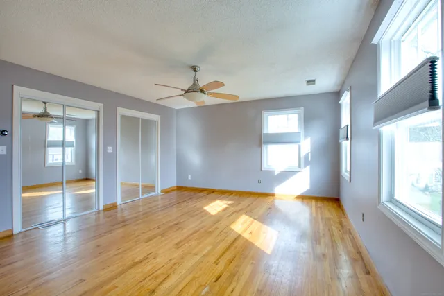 a view of empty room with wooden floor and fan