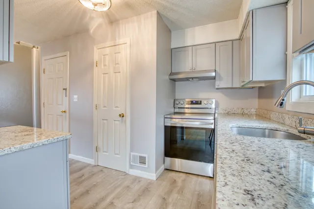 a kitchen with granite countertop a sink and a stove top oven