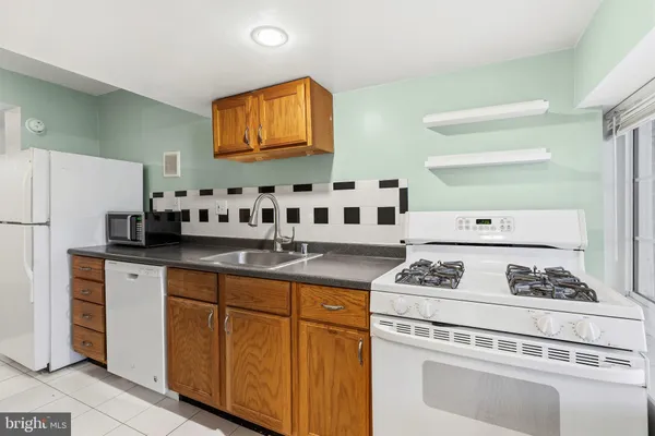 a white kitchen with stainless steel appliances granite countertop a stove a refrigerator and a white cabinets