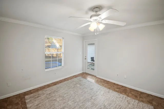an empty room with windows and fan