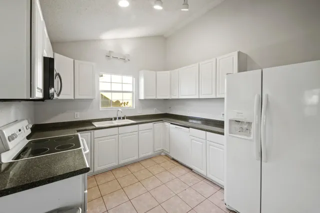 a kitchen with granite countertop white cabinets white stainless steel appliances and sink
