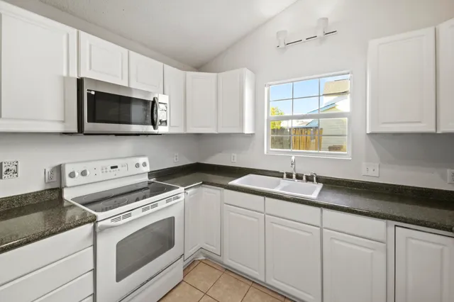 a kitchen with granite countertop white cabinets and white appliances