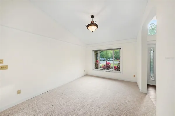 an empty room with windows and chandelier fan