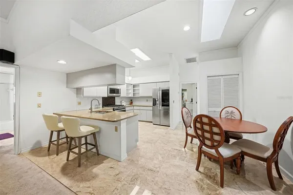 a kitchen with stainless steel appliances a dining table chairs and a refrigerator