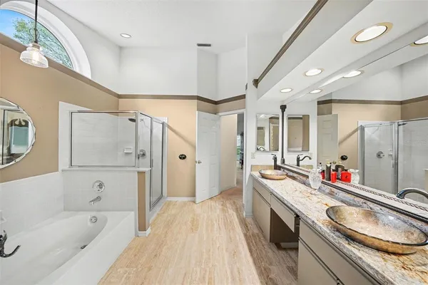 a bathroom with a granite countertop double vanity sink a mirror a bathtub and shower