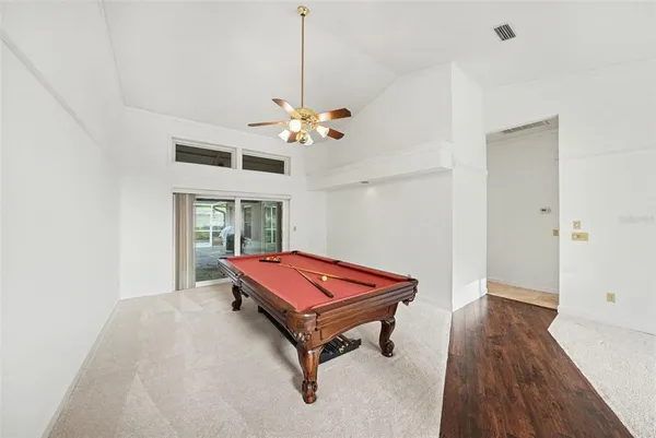 a room with pool table and wooden floor
