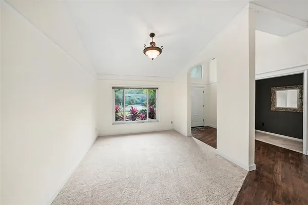 a view of an empty room with wooden floor and windows