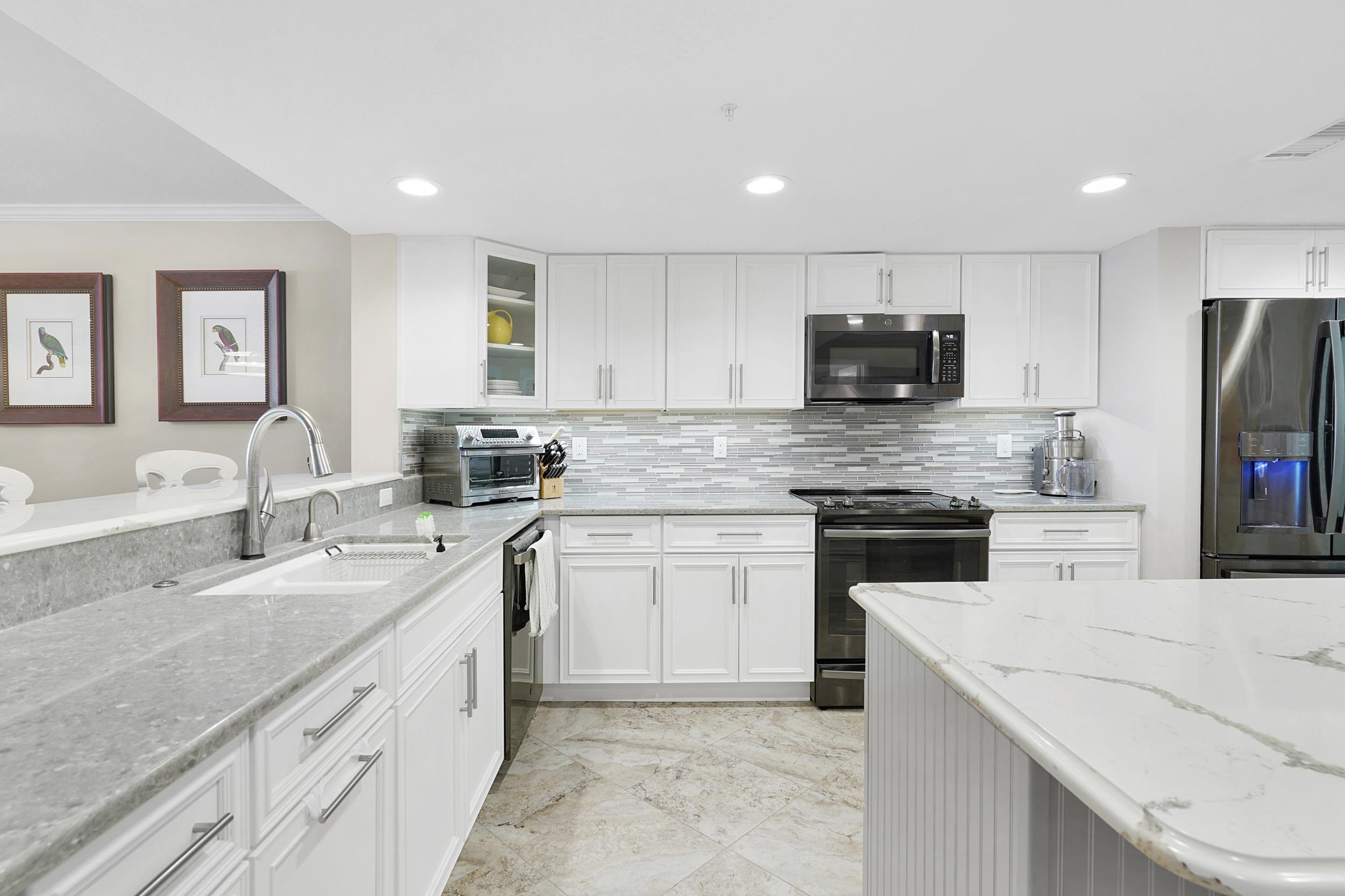33 Comares Avenue, Unit 203 St. Augustine, FL 32080 - Photo 8 of 39 Kitchen featuring appliances with stainless steel finishes, light stone counters, glass insert cabinets, white cabinetry, and recessed lighting