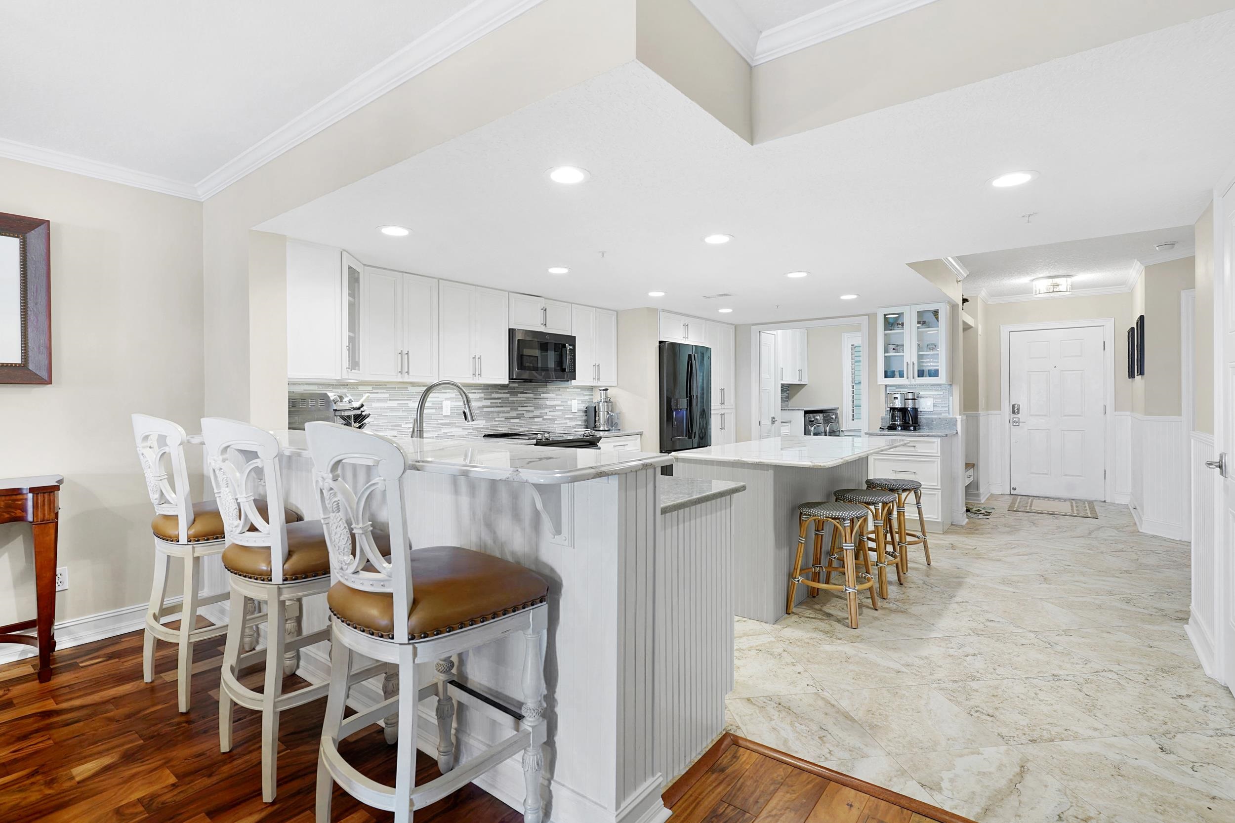 33 Comares Avenue, Unit 203 St. Augustine, FL 32080 - Photo 9 of 39 Kitchen with glass insert cabinets, a kitchen bar, ornamental molding, a peninsula, and a center island