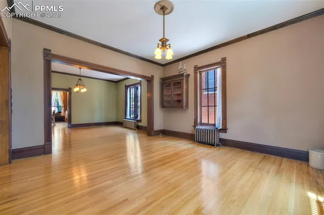 a view of an empty room with window and wooden floor