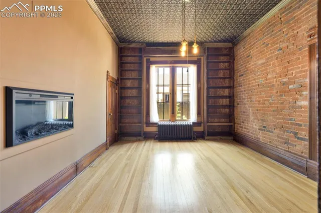 a view of an empty room with a window and wooden floor