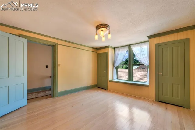 an empty room with wooden floor mirror and windows
