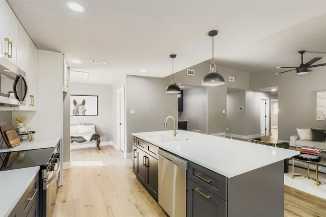 a large kitchen with a counter space a sink appliances and a wooden floor