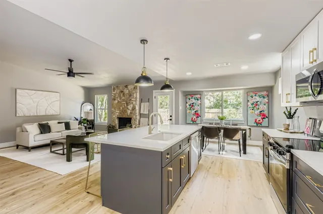 a large kitchen with a counter space a sink appliances and a large window