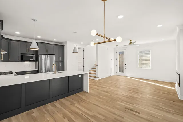 a large kitchen with kitchen island a sink stainless steel appliances and a chandelier