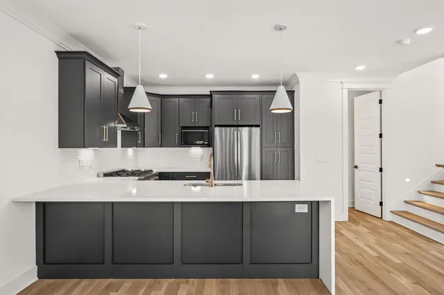 a large kitchen with stainless steel appliances a large counter top a stove a refrigerator and a sink