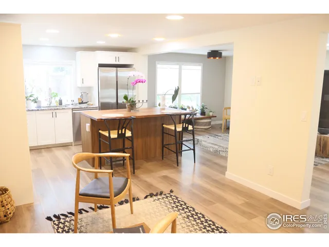 a dining room with kitchen island granite countertop wooden floor a rug and a window