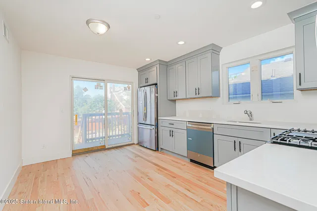 a kitchen with stainless steel appliances granite countertop a stove a sink dishwasher and a refrigerator with wooden floor