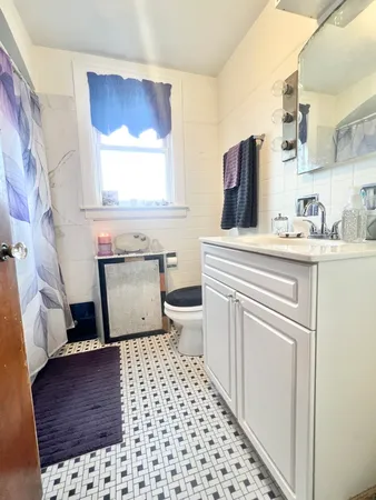 a bathroom with a sink a toilet a window and vanity