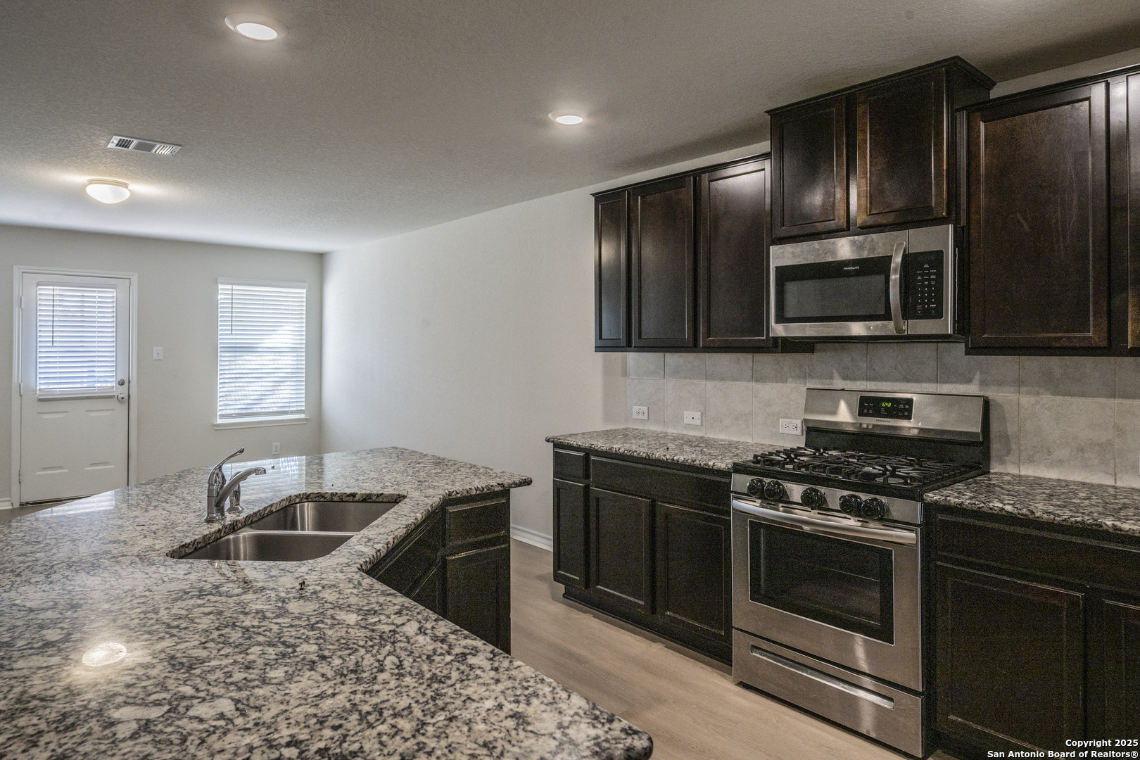 5914 Lazo Valley San Antonio, TX 78244 - Photo 13 of 40 a kitchen with granite countertop wooden cabinets stainless steel appliances and a window