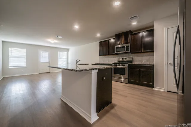 a kitchen with stainless steel appliances granite countertop a stove a sink and a refrigerator
