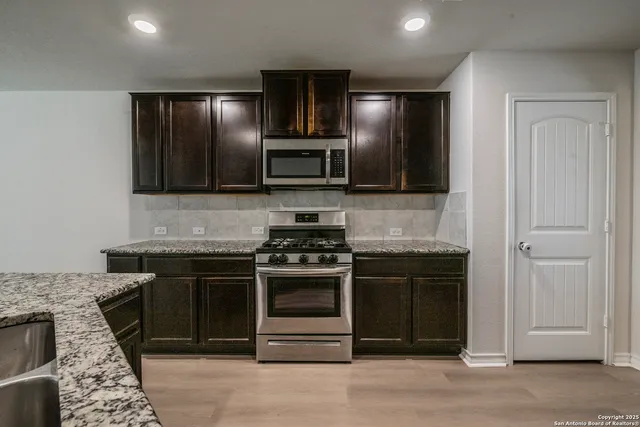 a kitchen with stainless steel appliances granite countertop a stove and a microwave
