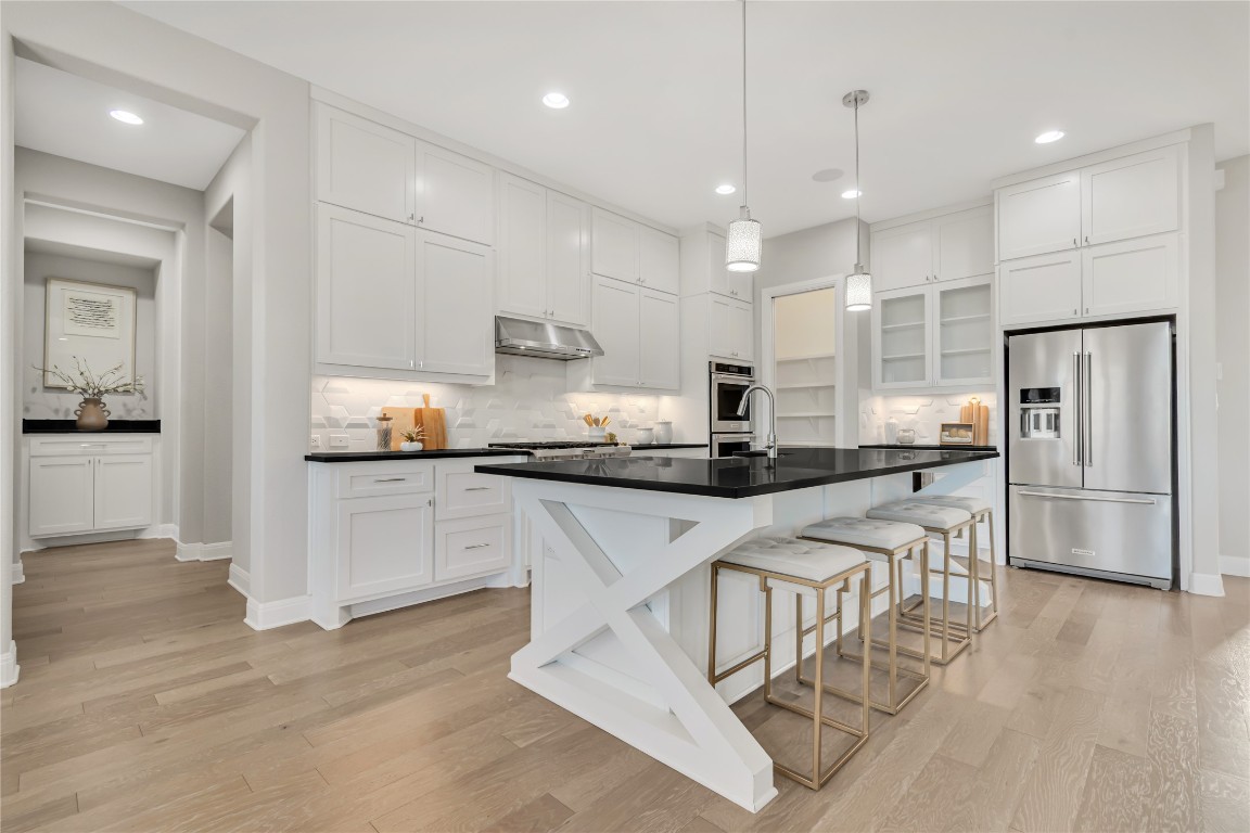 1700 Jackpot Run Leander, TX 78641 - Photo 12 of 40 a kitchen with stainless steel appliances granite countertop a refrigerator a sink dishwasher a stove and white cabinets with wooden floor
