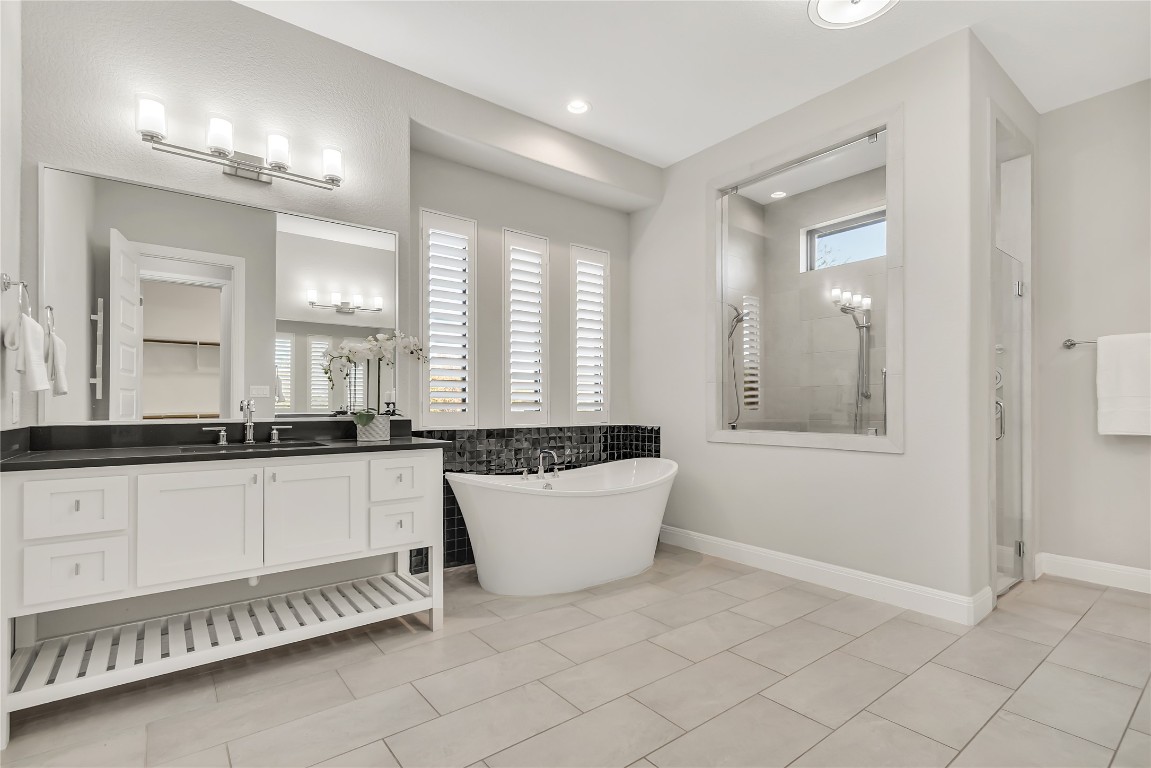 1700 Jackpot Run Leander, TX 78641 - Photo 23 of 40 a bathroom with a tub a double vanity sink and a mirror