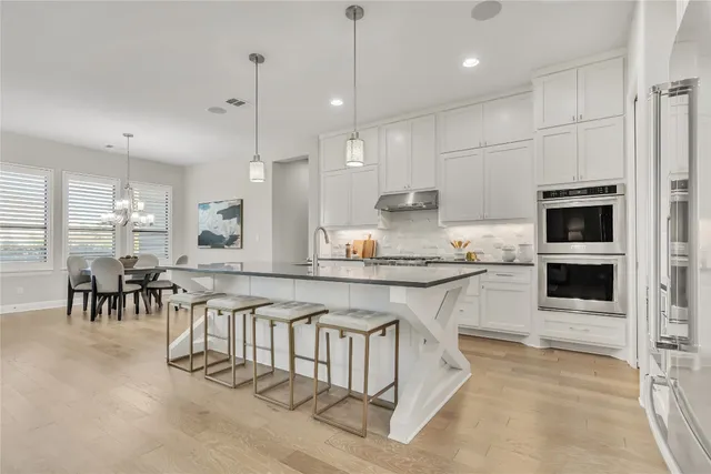 a large white kitchen with granite countertop lots of counter space and stainless steel appliances