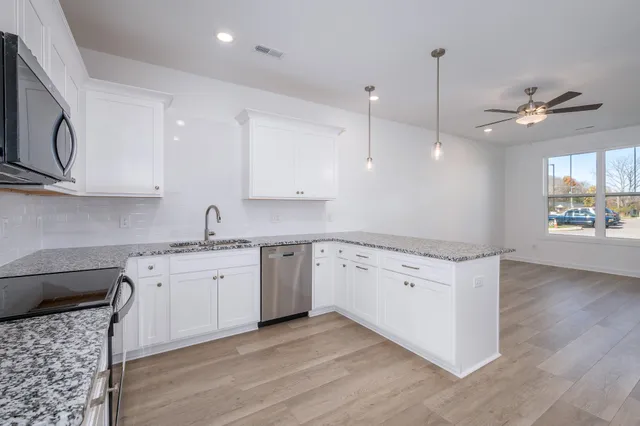 a kitchen with granite countertop a stove a sink a center island and wooden floor