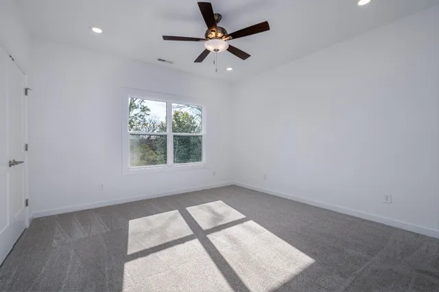 an empty room with windows and fan