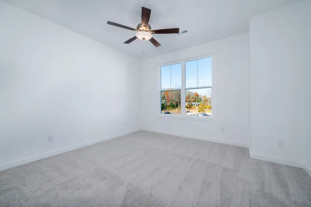 an empty room with window and ceiling fan