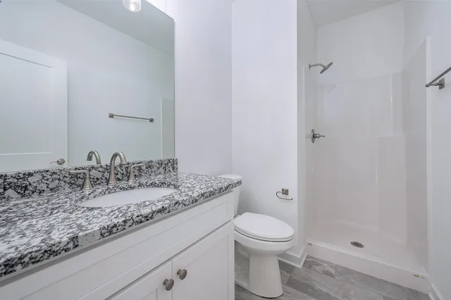 a bathroom with a granite countertop sink a toilet and shower
