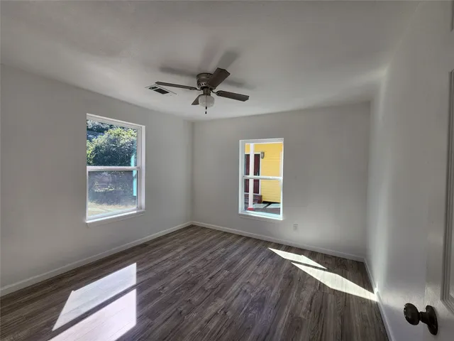 a view of an empty room with a window and wooden floor
