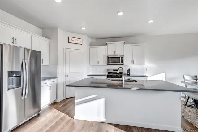 a kitchen with kitchen island white cabinets and stainless steel appliances