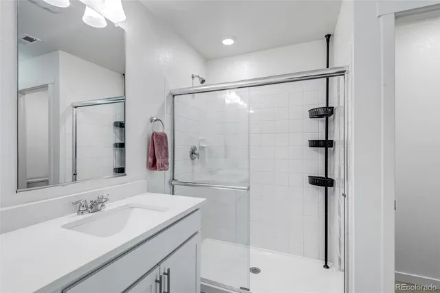 a bathroom with a granite countertop sink mirror shower and double