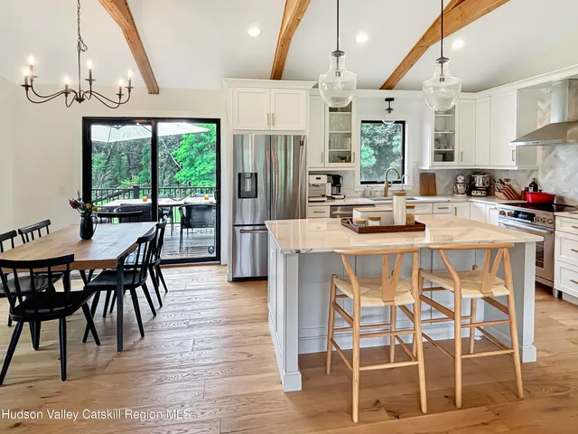a kitchen with stainless steel appliances kitchen island granite countertop a dining table chairs and white cabinets