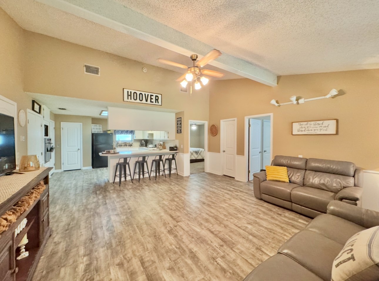 702 Pleasant Grove Road Elgin, TX 78621 - Photo 11 of 38 Living room with beam ceiling, a textured ceiling, wood finished floors, a ceiling fan, and high vaulted ceiling